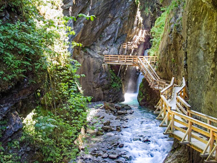 Eine beeindruckende Schlucht mit einem klaren Wasserlauf. Holzstege führen durch die grüne Landschaft.