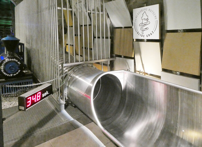 Graz, Schloßberg, Ausstieg der Rutsche mit Stoppuhr. Links eine Lok der Märchenbahn.