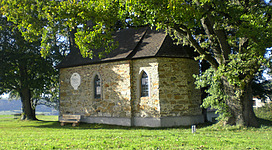 Kapelle umgeben von Wiese und Bäumen