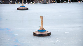 Zwei Spielsteine stehen auf einer spiegelglatten Eisfläche. Im Hintergrund sind Lichter zu sehen.