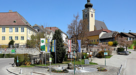 Südwestansicht des Zentrums bzw. des Marktplatzes von Kottes, ein Ortsteil und der Hauptort der niederösterreichischen Marktgemeinde Kottes-Purk. Im Hintergrund die weithin sichtbare röm.-kath. Pfarrkirche Mariä Himmelfahrt.