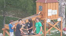 Eine Gruppe von Kindern steht an einem Holzspielplatz mit einem Wasserspiel. Sie haben Spaß und spielen zusammen.