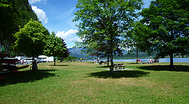 Abgebildet ist der Badeplatz mit schattenspendenden Bäumen.