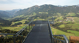 Eine Aussichtsplattform mit Blick auf grüne Täler und Berge. Der Himmel ist klar und die Landschaft ist sehr abwechslungsreich.