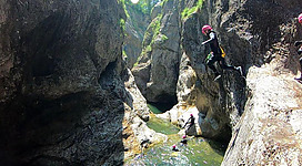 Eine natürliche Schlucht mit Wasser und hohen Felsen. Menschen springen ins Wasser und genießen die Aktivität.