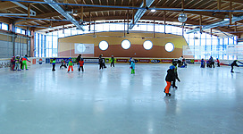 Personen beim Eislaufen in einer Halle