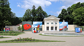 Pavillon der ehemaligen Orangerie im Doblhoffpark in der niederösterreichischen Stadt Baden mit Fotos der Open-Air Fotoausstellung Fotofestival La Gacilly-Baden 2018.Der ehemalige Schlosspark des Schlosses Weikersdorf ist nach dem Adelsgeschlecht Doblhoff benannt, die von 1741 bis zum Ankauf durch die Stadtgemeinde Baden im Jahr 1966 im Besitz des Schlosses und Parks waren. 1969 wurde ein Rosarium in dem rund 8 Hektar großen Park in Kooperation mit der Stadtgemeinde, den österreichischen Baumschulen und dem Architekt Viktor Mödlhammer eröffnet. 2018 wurden dabei ca. 600 Rosensorten präsentiert.