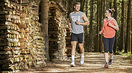 Foto SINNVIERTEL Tourismus_Johannes Kernmayer: Jogger und Joggerin im Wald mit sportlicher Kleidung auf den Wegen der Bewegungs-Arena Innviertel