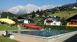 Ein schöner Swimmingpool in einer alpinen Umgebung mit Blick auf die Berge. Feriengäste genießen den Sonnenbad und das Wasser.