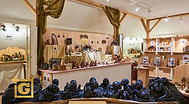 Ein kunsthandwerklicher Verkaufsstand mit verschiedenen hölzernen Skulpturen aus Tansania. Im Vordergrund sind mehrere Schwarzholzfiguren von Menschen zu sehen.
