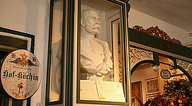 Hausmuseum „Auf den Spuren der Habsburger“ in Weyregg am Attersee: Das Bild zeigt eine dekorative Skulptur, die einen bärtigen Mann darstellt. Umgeben ist die Skulptur von historischen, mit Ornamenten verzierten Rahmen und Übergängen, die einen traditionellen und authentischen Eindruck vermitteln.