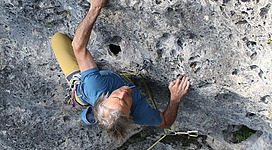 Ein Kletterer, der an einer Felswand klettert. Er nutzt seine Hände und Füße, um die herausfordernde Strecke zu bewältigen.