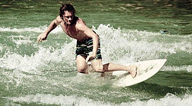 Ein Surfer reitet auf den Wellen und zeigt Geschick auf seinem Surfbrett. Die Wasseroberfläche spritzt spritzig um ihn herum.