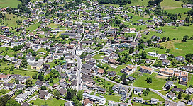 Schrägluftbild der Kath. Pfarrkirche hl. Georg, Friedhof und Volksschule als Teil der Übersichtsansicht der Gemeinde.