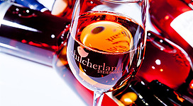 Ein elegantes Glas Roséwein steht vor einer Ansammlung von Weinflaschen. Die Farben des Weins und der Flaschen erzeugen eine ansprechende, festliche Atmosphäre.