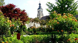 Literaturgarten in St. Florian: Ein malerischer Ort mit einem historischen Gebäude, umgeben von üppigen Grünanlagen und bunten Blumen. Die Architektur des Gebäudes wirkt gepflegt und stimmungsvoll. Die Umgebung ist liebevoll gestaltet mit Bäumen, Sträuchern und blühenden Blumenbeeten.