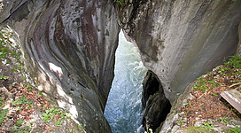 Eine beeindruckende Schlucht mit steilen Felswänden und fließendem Wasser. Das Licht spiegelt sich im Wasser und schafft eine mystische Atmosphäre.