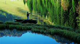 In Zauchensee ist ein Fliegenfischer auf einem Boot im Wasser und angelt gerade seine Beute bei schönsten Wetter.
