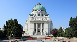 Nordostansicht der römisch-katholischen Karl-Borromäus-Kirche, auch Luegerkirche (Dr.-Karl-Lueger-Gedächtniskirche) bezeichnet, am Zentralfriedhof im 11. Wiener Gemeindebezirk Simmering und davor die Präsidentengruft. Die Kirche wurde von 1908 bis 1911 nach Entwürfen des Architekten Max Hegele errichtet. Ende Oktober 1910 wurden die sterblichen Überreste des Wiener Bürgermeister Karl Lueger in der Kirchengruft unter dem Hochaltar beigesetzt.