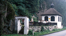 Einsiedlerhaus Schwertberg in Schwertberg: Ein malerisches Gebäude mit einem Turm und Steinmauern, umgeben von grüner Vegetation und felsigen Bergen in der Umgebung. Eine Treppe führt an den Eingang des Gebäudes. Das Gesamtbild vermittelt einen ländlichen, romantischen Eindruck.