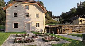 Außenansicht des stilvoll renovierten Pflegerschlössls in Wagrain, welches das Stille Nacht Museum beherbergt. Ein barockes Gebäude mit einem modernen, sehr gelungenen Anbau und der markanten Textskulptur an der Fassade dieses Anbaus.