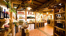 Ein gemütlicher Verkaufsraum mit Regalen voller Weinflaschen und Spirituosen. Die rustikale Einrichtung schafft eine einladende Atmosphäre.