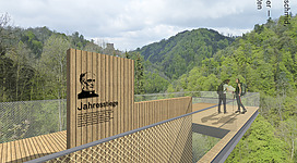 Jahresstiege mit Waldlehrpfad in Gramastetten: Auf einer erhöhten Holzplattform stehen zwei Wanderer und genießen die umliegende Berglandschaft. Am Eingang des Weges befindet sich eine Infotafel, die auf den "Jahresstieg" hinweist. Die Umgebung ist geprägt von dichten Wäldern und Gebirgszügen.