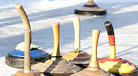 Eine Gruppe von Holzspielzeugen auf einer glatten Eisfläche. Die Spielzeuge haben unterschiedliche Farben und Formen.