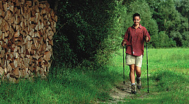Zu sehen ist eine Frau beim Wandern durch den Wald.