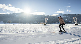 Frau beim Langlaufen vor sonniger Bergkulisse im Salzburger Land