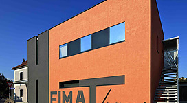 Heimathaus Stadtmuseum Perg in Perg: Ein modernes, zweigeschossiges Gebäude mit einer auffallenden orangefarbenen Fassade. Es besitzt große Fenster an der Fassade und eine Freitreppe an der Seitenfassade. Der Schriftzug "EIMA haus" ist deutlich an der Vorderseite erkennbar.