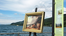 Kulturwanderweg Steinbach am Attersee in Steinbach am Attersee: Das Bild zeigt eine Landschaftsszene mit einem alten Gebäude in einer ländlichen Umgebung. Im Vordergrund sind einige Pferde zu sehen, die eine Szene der Ruhe und Naturverbundenheit darstellen.