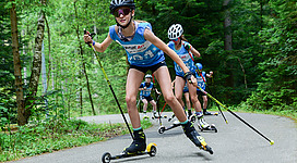 Foto S'INNVIERTEL TOURISMUS/FotoloungeBlende8: Mehrere junge Mädels und Burschen fahren auf Skirollern durch den Kobernaußerwald. Alle sind sportlich gekleidet und haben ein blaues Trikot mit der Startnummer.