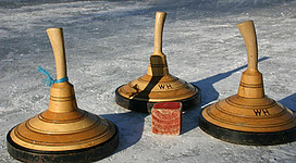 Drei Holzschleifen stehen auf einer gefrorenen Fläche. In der Mitte befindet sich ein roter Block.