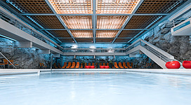 Ein modernes Schwimmbad mit klarem Wasser und einem attraktiven Design. Die Wände sind mit Felsen versehen und es gibt bequeme Liegen in warmen Farben.