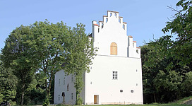 BURG OBERNBERG, KUNSTHAUS - SEMINARHAUS in Obernberg am Inn: Ein mehrstöckiges Gebäude mit weißer Fassade, das an eine traditionelle Architektur erinnert. Das Gebäude ist von Bäumen und grüner Vegetation umgeben, was eine angenehme, natürliche Umgebung schafft.
